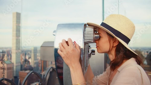 Young tourist looking through binoculars at the viewpoint in New York