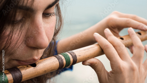 Slika na platnu Musician playing a wooden flute on the banks of the river