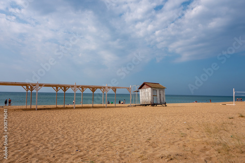 The empty beach on the sea in autumn with a small abandoned cloakroom. Cloudy sky in the afternoon