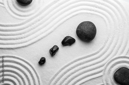 Black stones on sand with pattern, top view. Zen, meditation, harmony
