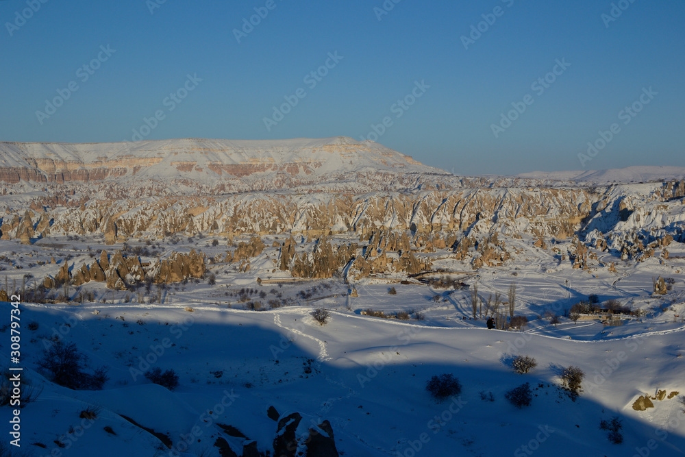 Beautiful snowy winter view of unusual rock formations in Cappadocia near Goreme before sunset
