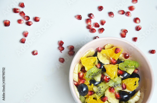 salad with fresh fruits and berries made from orange grapes and pomegranate and kiwi on a black background diet healthy nutrition vegetarianism