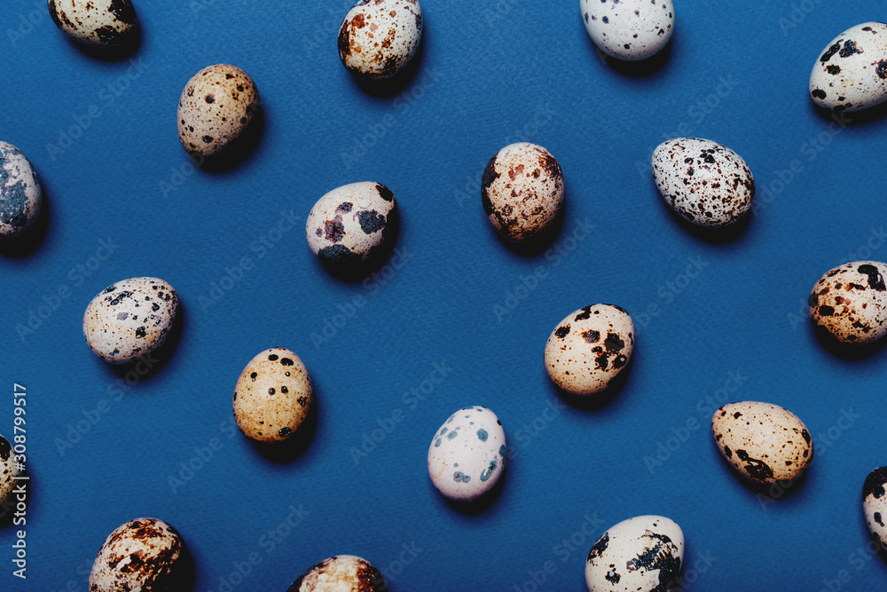 Small quail eggs on a blue paper perforated background. Classic easter concept in the trend of 2020. Seamless pattern, top view, flat lay