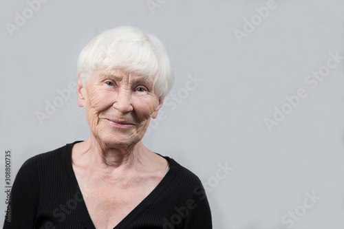 Portrait of an elderly woman on a gray background . Close up.