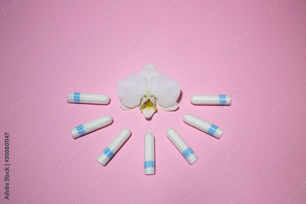 The concept female intimate hygiene. Cotton tampons on a pink background. Menstrual cycle. Critical days in women. Template for design or social advertising. Orchid flower. Place for text.