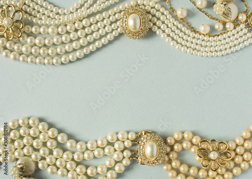 Woman's Jewelry. Vintage jewelry background. Beautiful gold tone and pearls brooches, braceletes, necklaces and earrings on blue background. Flat lay, top view.
