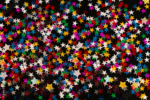 Black abstract background with multicolored particles like snow stars for use on Christmas or New year banners flyers greeting cards. Vector image