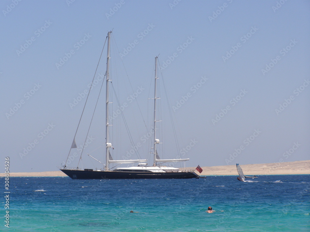 Seascape. Sailing ship in the blue sea on a background of blue sky and islands.