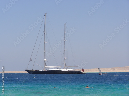 Seascape. Sailing ship in the blue sea on a background of blue sky and islands.