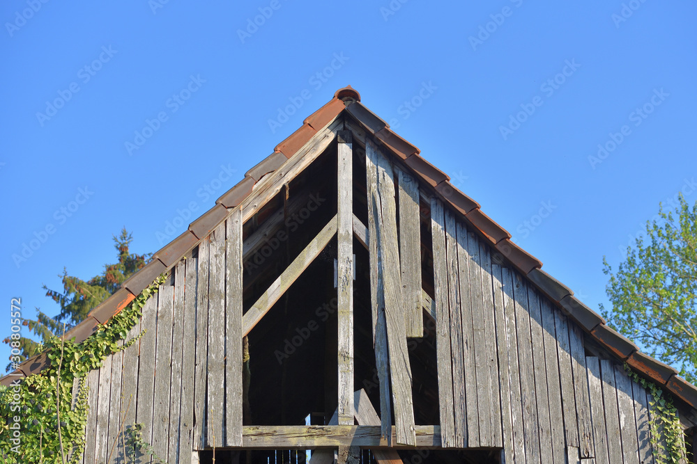 Old wooden and holey shed roof against a blue sky in a European village Old wooden and holey shed roof against a blue sky in a European village