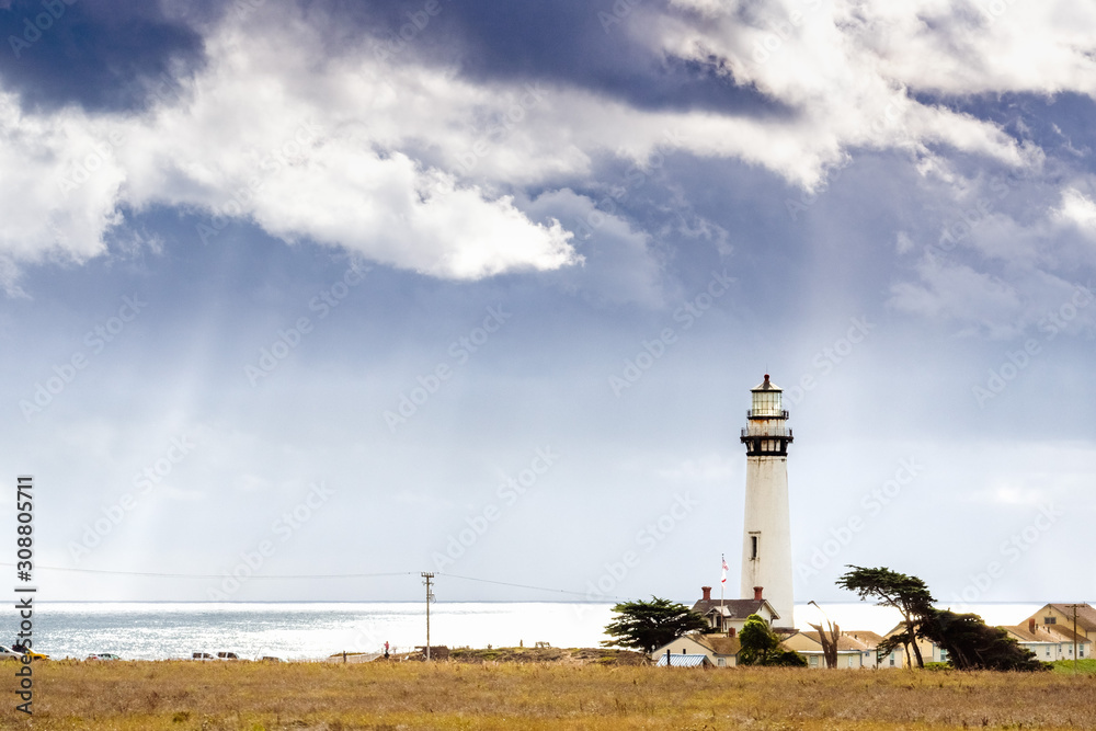 Pigeon Point Lighthouse on the Pacific Ocean coastline; sun rays bursting through storm clouds; Pescadero, San Francisco bay area, California