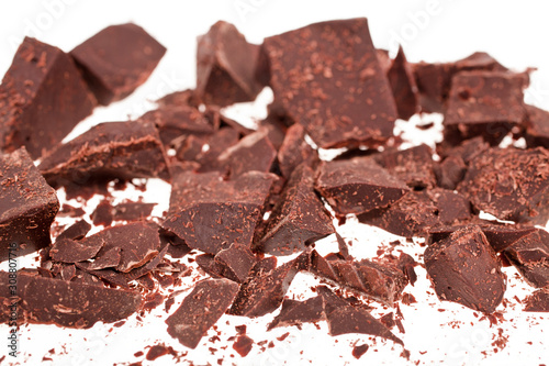 Chopped chocolate pieces on white background. Selective focus.