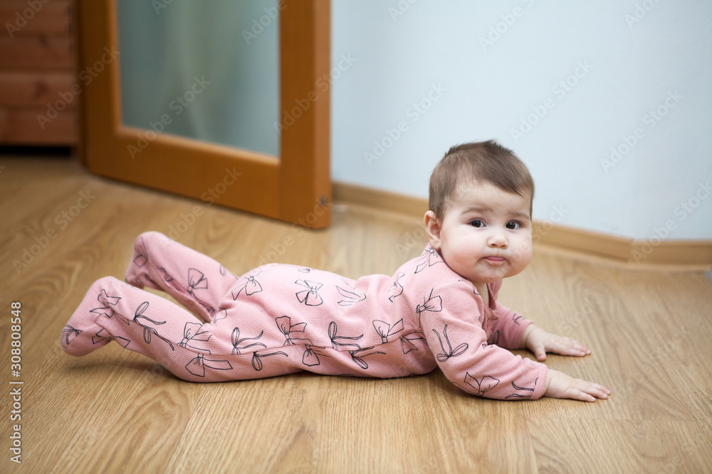 Portrait of Caucasian baby lying on floor in domestic room, creeper Portrait of Caucasian baby lying on floor in domestic room, creeper