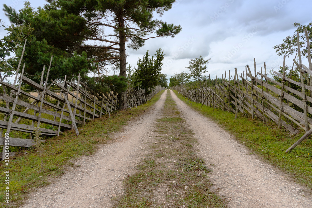 Landscape on the island Gotland, Sweden, with dirtway and typical wooden fences. Sky with dramatic clouds. Landscape on the island Gotland, Sweden, with dirtway and typical wooden fences. Sky with dramatic clouds.
