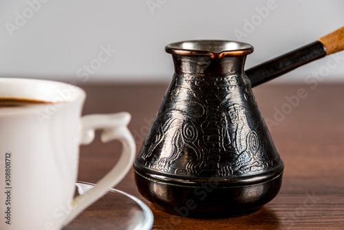 Cezve and a cup of coffee on a wooden table © Andrey Nikitin