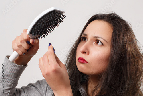 a girl with tousled shaggy hair holds a comb in her hands photo