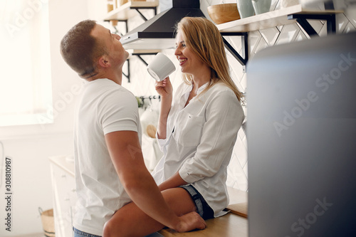 Cute couple in a kitchen. Lady in a white shirt. Pair at home