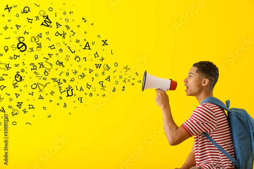 Portrait of African-American teenage boy with megaphone on color background photo