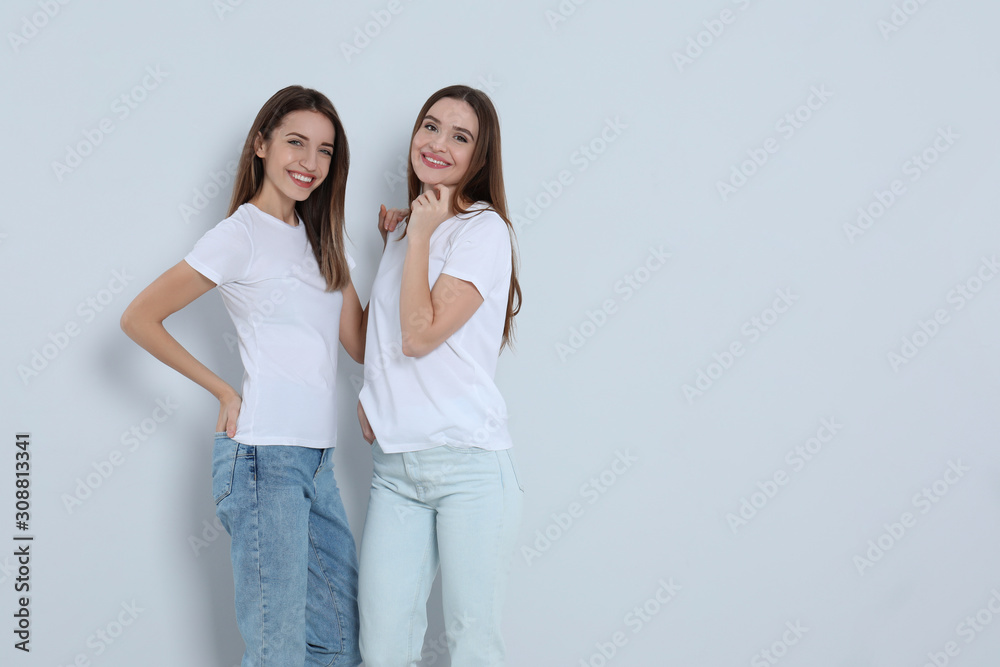 Young women in stylish jeans on light background. Space for text Young women in stylish jeans on light background. Space for text