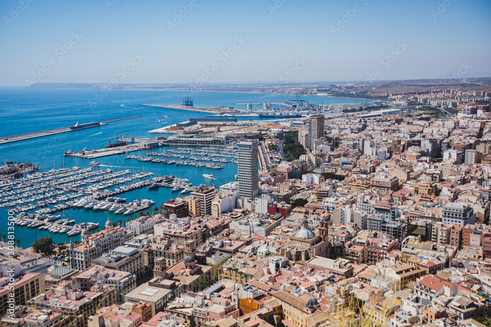 Fototapeta premium Beautiful wide aerial view of Alicante, Valencian Community, Spain with port of Alicante, beach and marina, with mountains and skyline, seen from Santa Barbara Castle on Mount Benacantil, sunny day