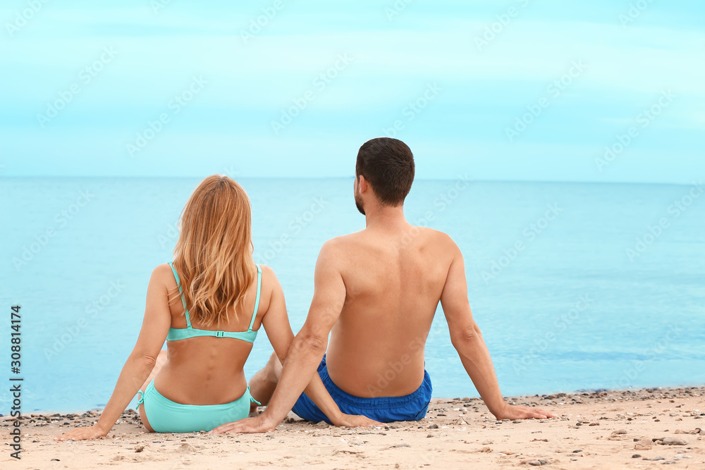 Happy couple sitting on beach at sea resort Happy couple sitting on beach at sea resort