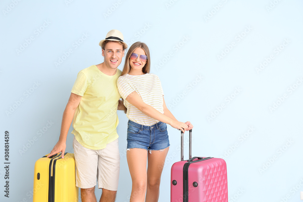 Young couple with suitcases on light background Young couple with suitcases on light background