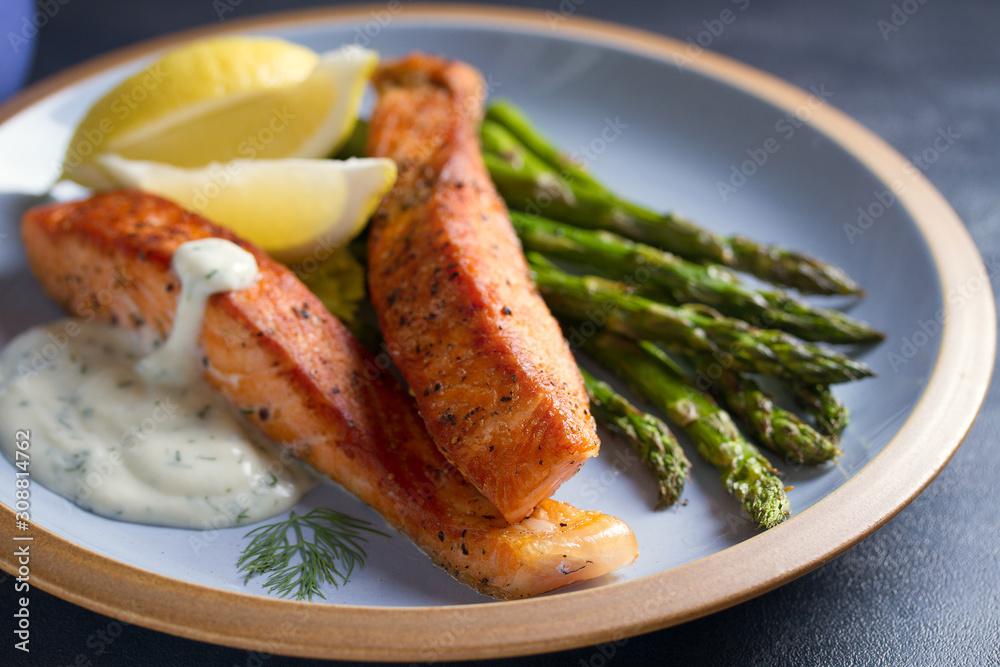 Delicious cooked salmon fish fillets with asparagus and lemon wedges Delicious cooked salmon fish fillets with asparagus and lemon wedges
