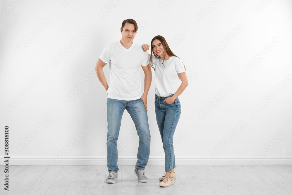 Young couple in stylish jeans near white wall Young couple in stylish jeans near white wall