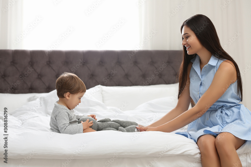 Young nanny and cute little baby playing with toy in bedroom Young nanny and cute little baby playing with toy in bedroom