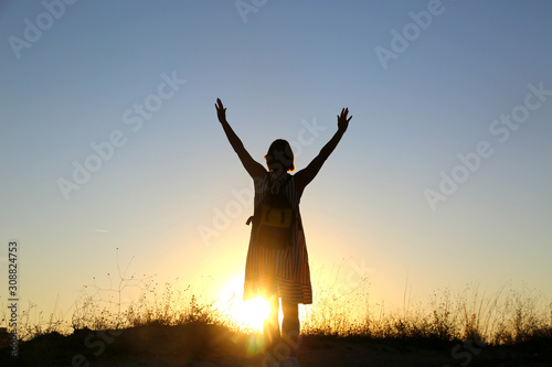 Powerful woman traveller hands up in the air enjoys sunrise. Freedom lifestyle.