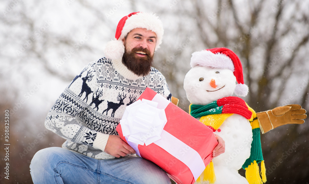 Cheerful and positive. bearded man build snowman. Happy new year. winter season. Merry christmas. man give present outdoor. winter holiday. warm sweater in cold weather. happy hipster ready for xmas
