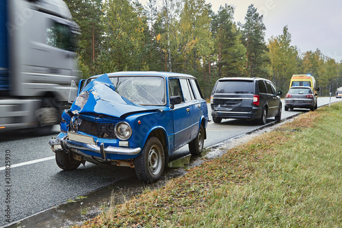 damaged old car on the highway at the scene of an accident