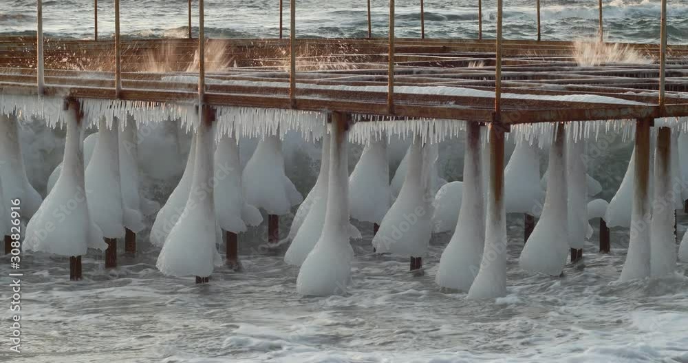 Ocean waves breaking through the frozen pier Ocean waves breaking through the frozen pier