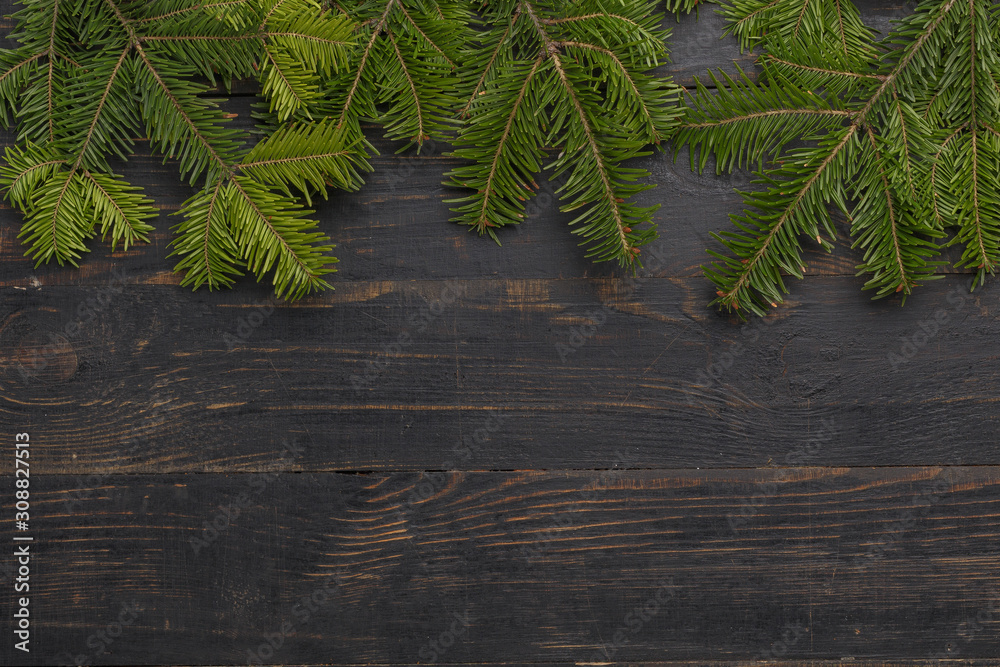 Spruce branches on a black wooden background. View from above Spruce branches on a black wooden background. View from above