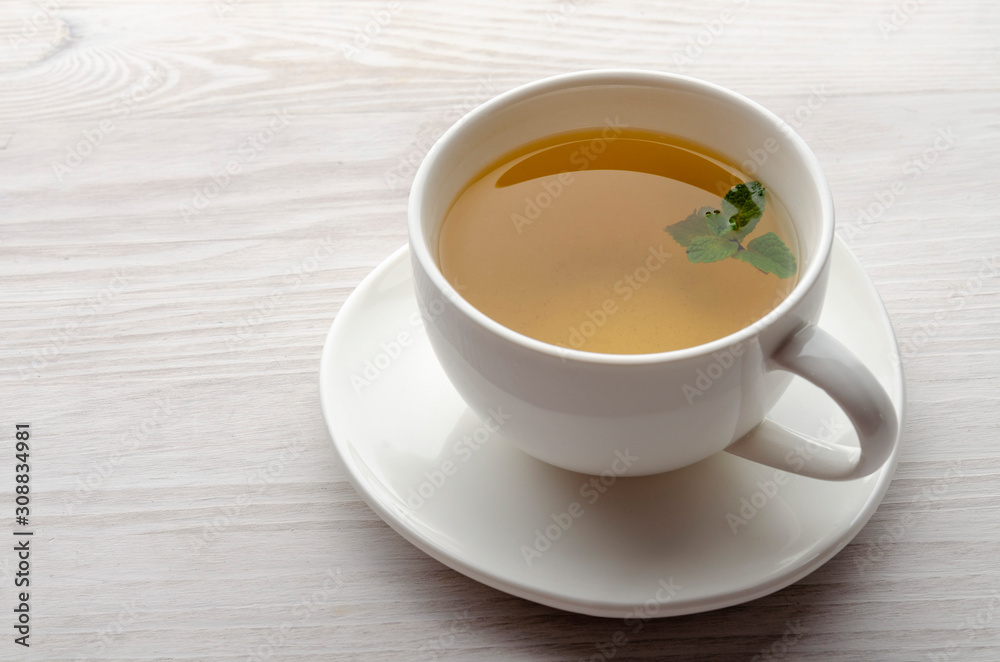 Cup and teapot of herbal tea with fresh mint on wooden boards Cup and teapot of herbal tea with fresh mint on wooden boards