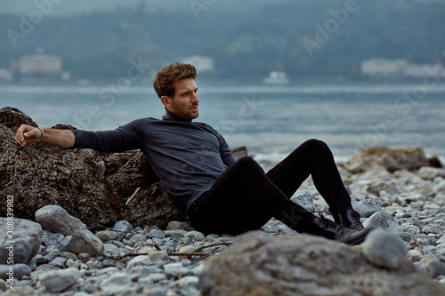 Fashionable male model outdoor sitting near the lake