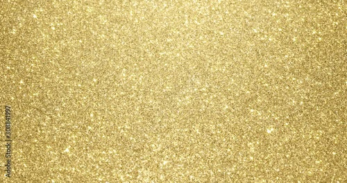 Gold glitter background with sparkling texture. Golden shimmering light, stars sequins sparks and glittering glow foil background