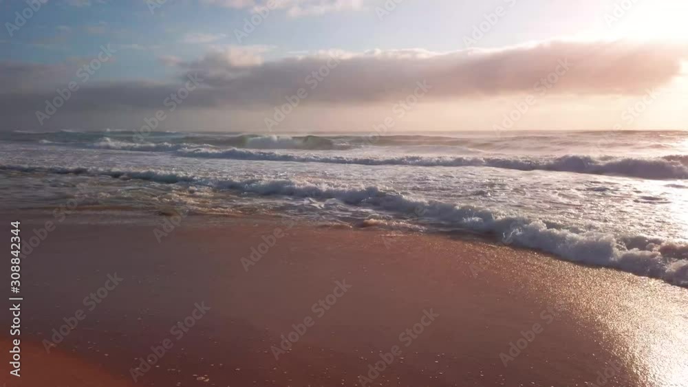 Waves and surf lapping at the golden shores of Cape Vidal, St. Lucia, South Africa, warm ocean water, mostly sunny, partly cloudy, sunrise