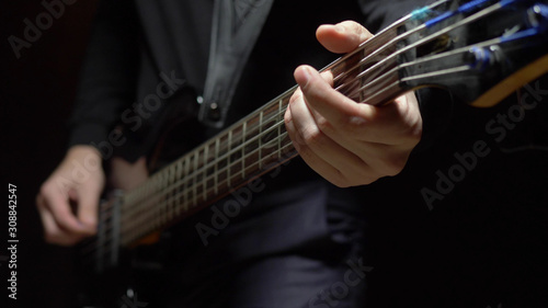man plays the bass guitar. Dark background. slowmo