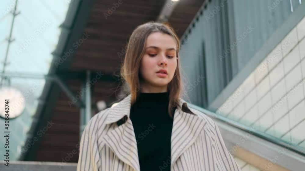 Attractive casual girl looking around confidently walking down the stairs at subway station