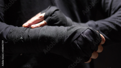 closeup. male hands wrapped around a black elastic bandage on hand. © kopitinphoto