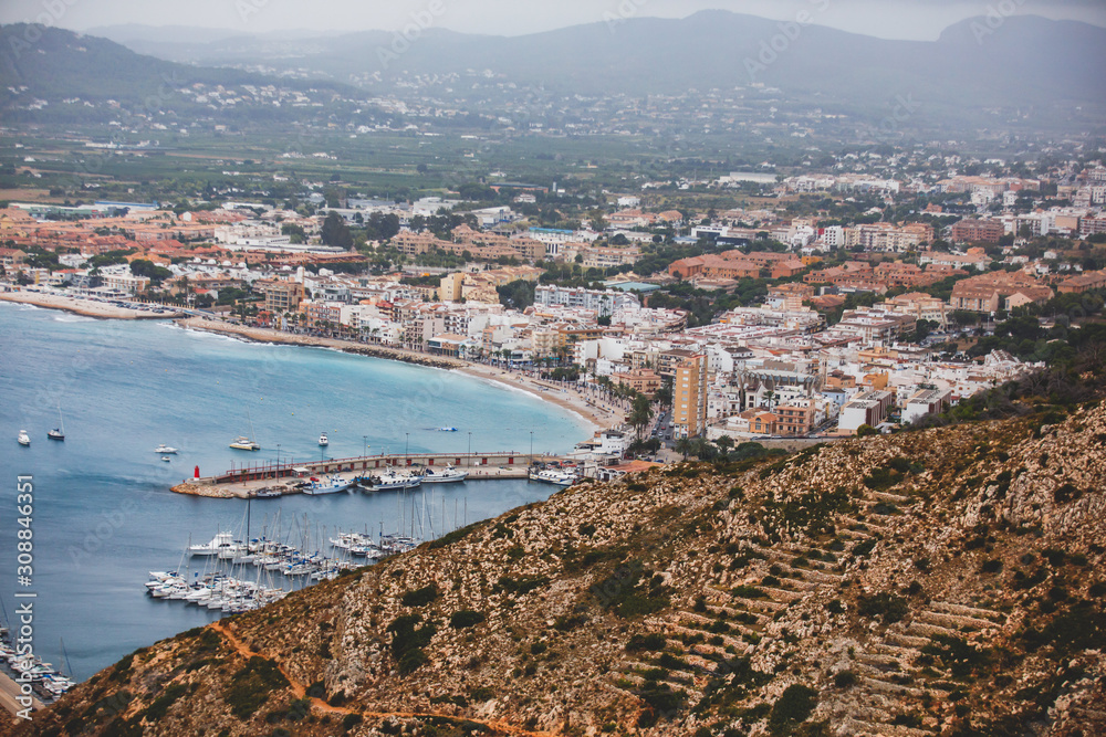 Beautiful super wide-angle aerial view of Xabia, Javea, Marina Alta with harbor and skyline, mountains, beach and city, seen from Cabo de San Antonio viewpoint, province of Alicante, Valencia, Spain