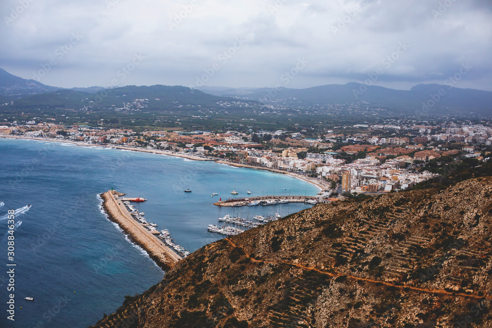 Beautiful super wide-angle aerial view of Xabia, Javea, Marina Alta with harbor and skyline, mountains, beach and city, seen from Cabo de San Antonio viewpoint, province of Alicante, Valencia, Spain