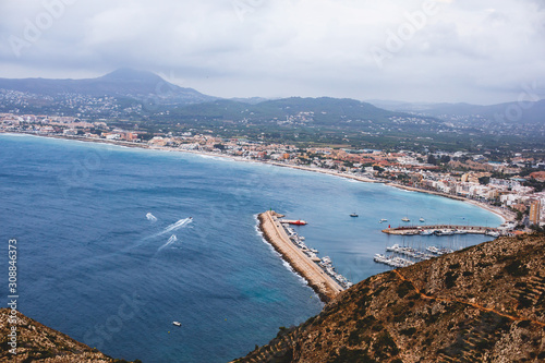 Beautiful super wide-angle aerial view of Xabia, Javea, Marina Alta with harbor and skyline, mountains, beach and city, seen from Cabo de San Antonio viewpoint, province of Alicante, Valencia, Spain photo