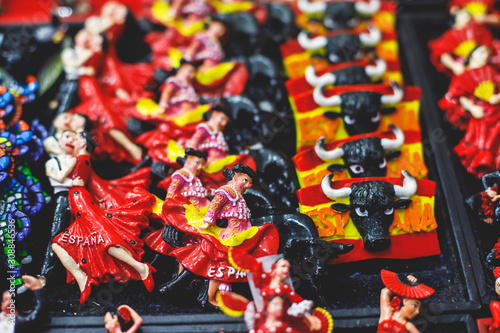 View of traditional tourist souvenirs and gifts from Spain, Alicante, Valencia with toys, bull figures, flamenco dancer dolls, fridge magnets with and key ring keychain, in local vendor souvenir shop