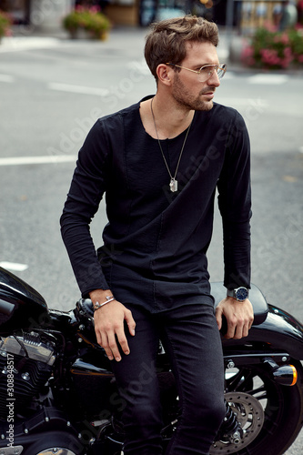 Handsome man in black sitting on classic motorbike