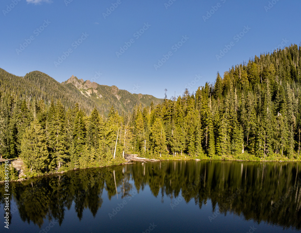 Secluded Kelcema Lake and the surrounding mountain and trees reflecting in the shaded water on a clear summer afternoon in the Mount Baker-Snoqualmie National Forest in Silverton Washington State Secluded Kelcema Lake and the surrounding mountain and trees reflecting in the shaded water on a clear summer afternoon in the Mount Baker-Snoqualmie National Forest in Silverton Washington State