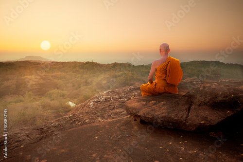 Buddhist monk in meditation at beautiful sunset or sunrise background on high mountain