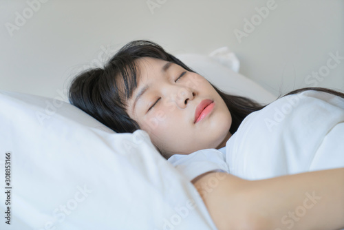 asian Young beautiful woman sleeping in her bed and relaxing in the morning