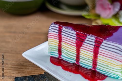 Fototapeta Naklejka Na Ścianę i Meble -  Colorful crape cake with strawberry syrup on white plate